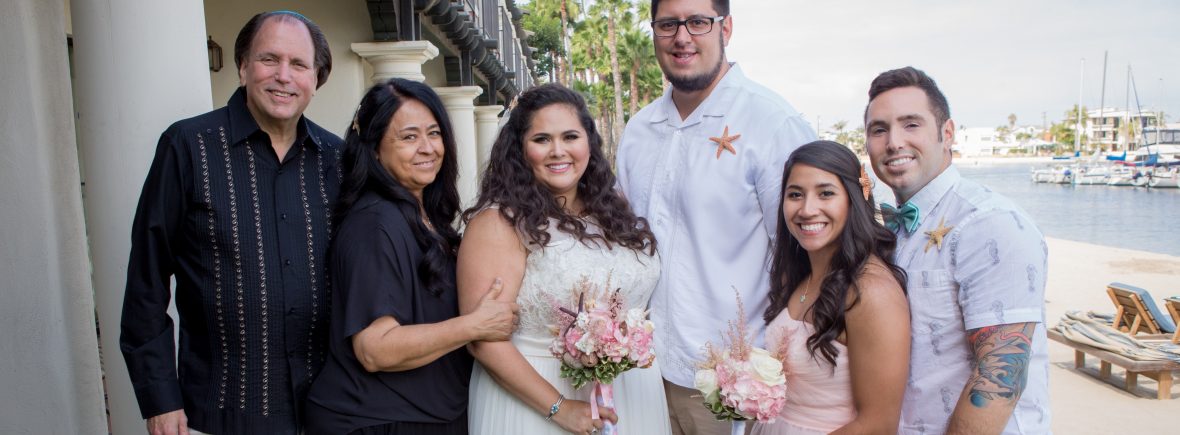 Photo of Davi on her wedding day. She is surrounded by her mom, dad, sister in law, brother and husband. They are all smiling and looking at the camera.